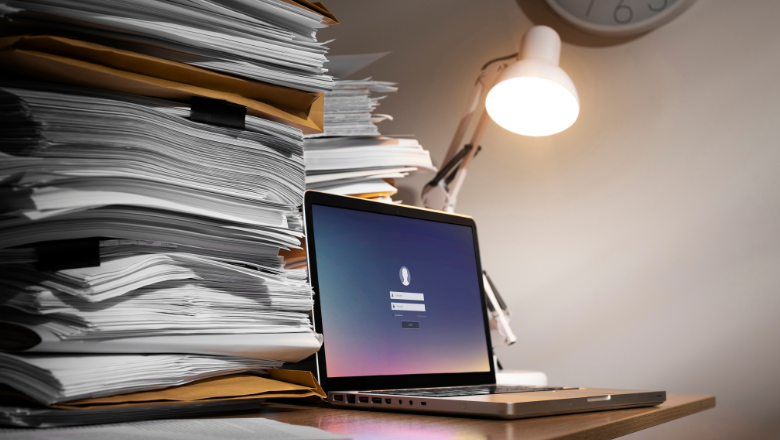 Verfahrensdokumentation Laptop zwischen Papierstapeln als Symbol für die Verfahrensdokumentation in der Buchhaltung.