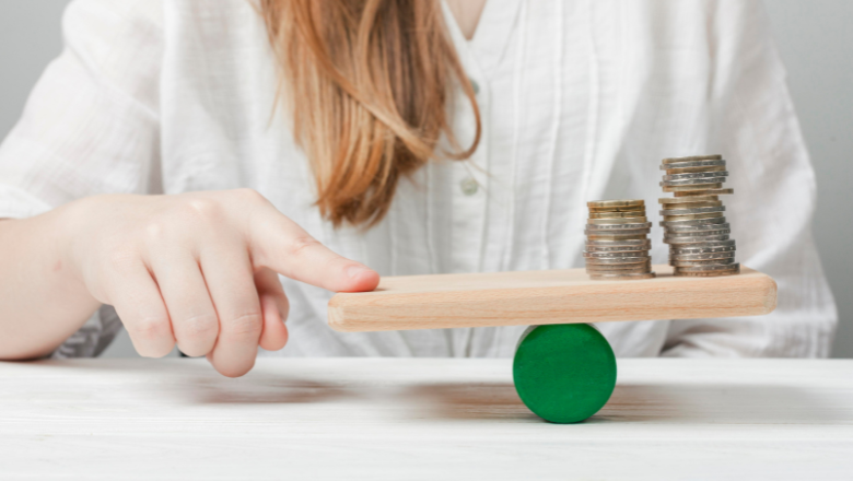 Gewinnermittlung - EÜR - Bilanz Hand balanciert Münzstapel auf einer Wippe – sinnbildlich für die Gewinnermittlung als Gleichgewicht von Einnahmen und Ausgaben.