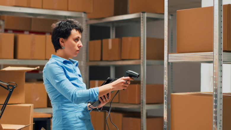 Mitarbeiterin erfasst Kartons im Lager mit Scanner als Teil vom Inventar