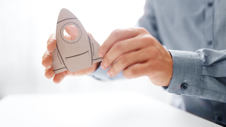Mini-GmbH Symbolische Darstellung einer Mini GmbH-Gründung: Person hält eine selbstgebastelte Rakete als Start-up-Symbol in den Händen.